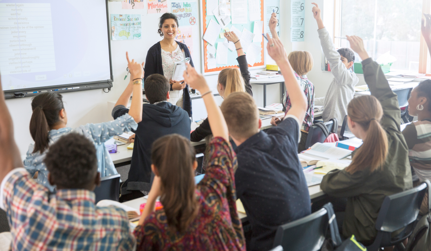 Classroom-Ready K–8 Programs That Work Students raising their hands in a classroom, waiting for the teacher to call on them.