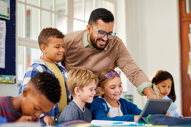 Teacher assisting students on a tablet.